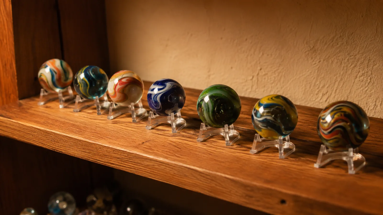 A row of glass marbles, one per small clear acrylic easel stand, lined across a wooden cabinet shelf in warm light